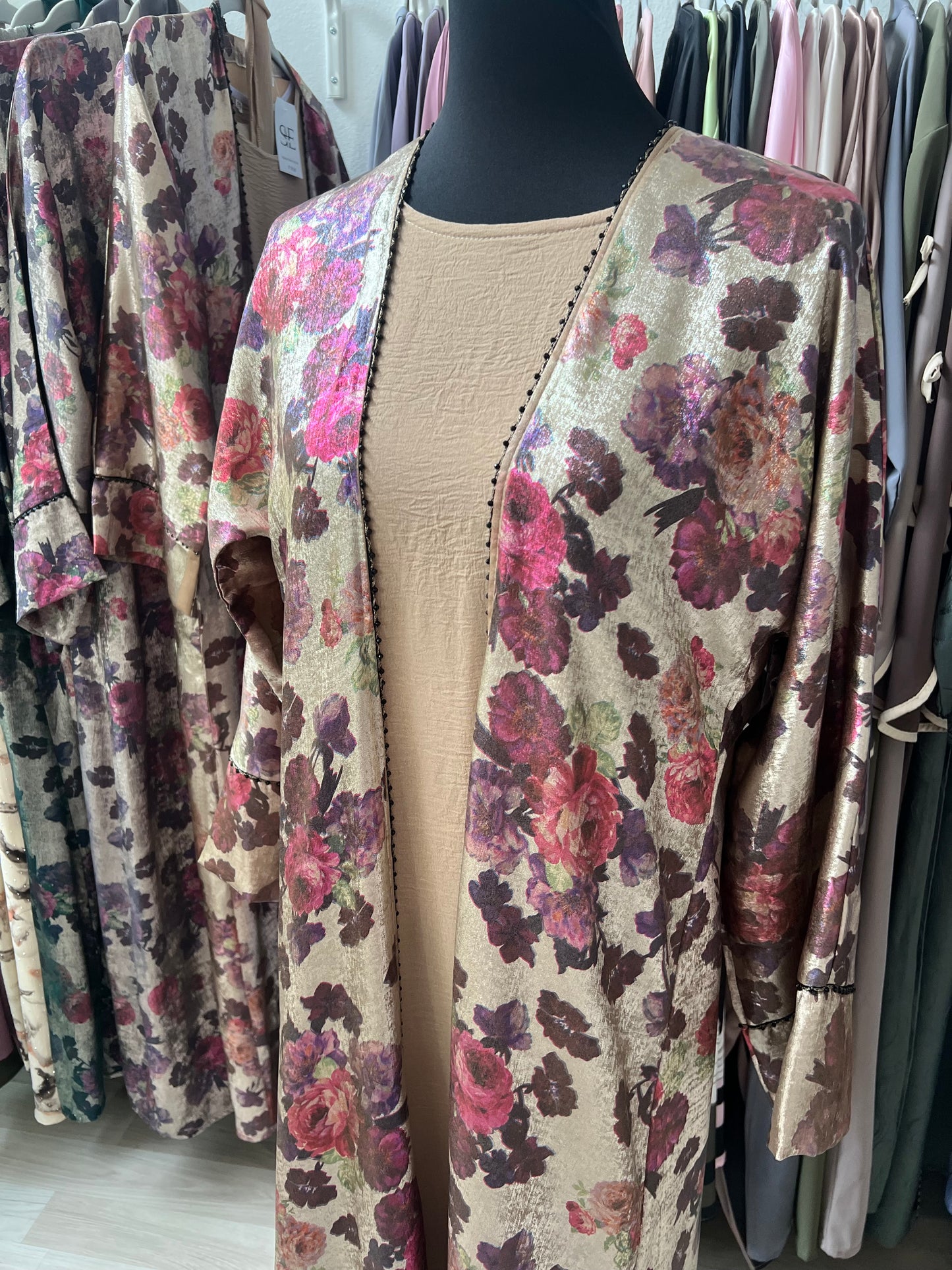 Abaya Rania aus floraler Jacquard-Seide mit dunklem Innenkleid – Nahaufnahme auf Brusthöhe, der schwarze Perlenbesatz hebt sich elegant ab.“