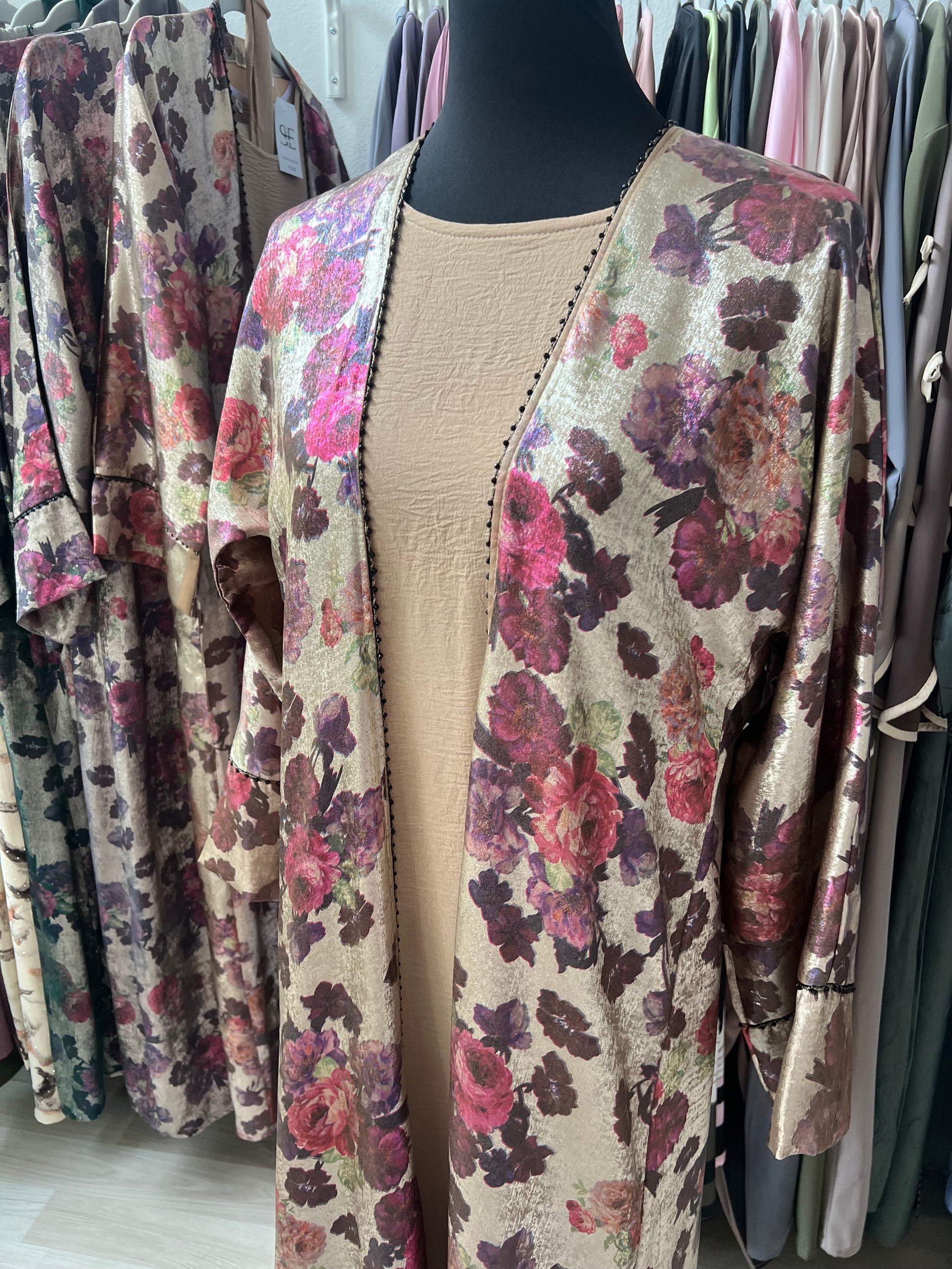 Abaya Rania aus floraler Jacquard-Seide mit dunklem Innenkleid – Nahaufnahme auf Brusthöhe, der schwarze Perlenbesatz hebt sich elegant ab.“