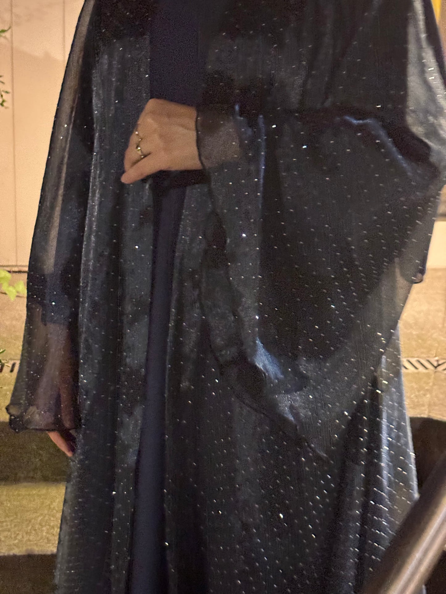 Abaya Sheyla Midnight Sky – Detailansicht der transparenten Glitzerärmel und schimmernden Struktur bei Nacht