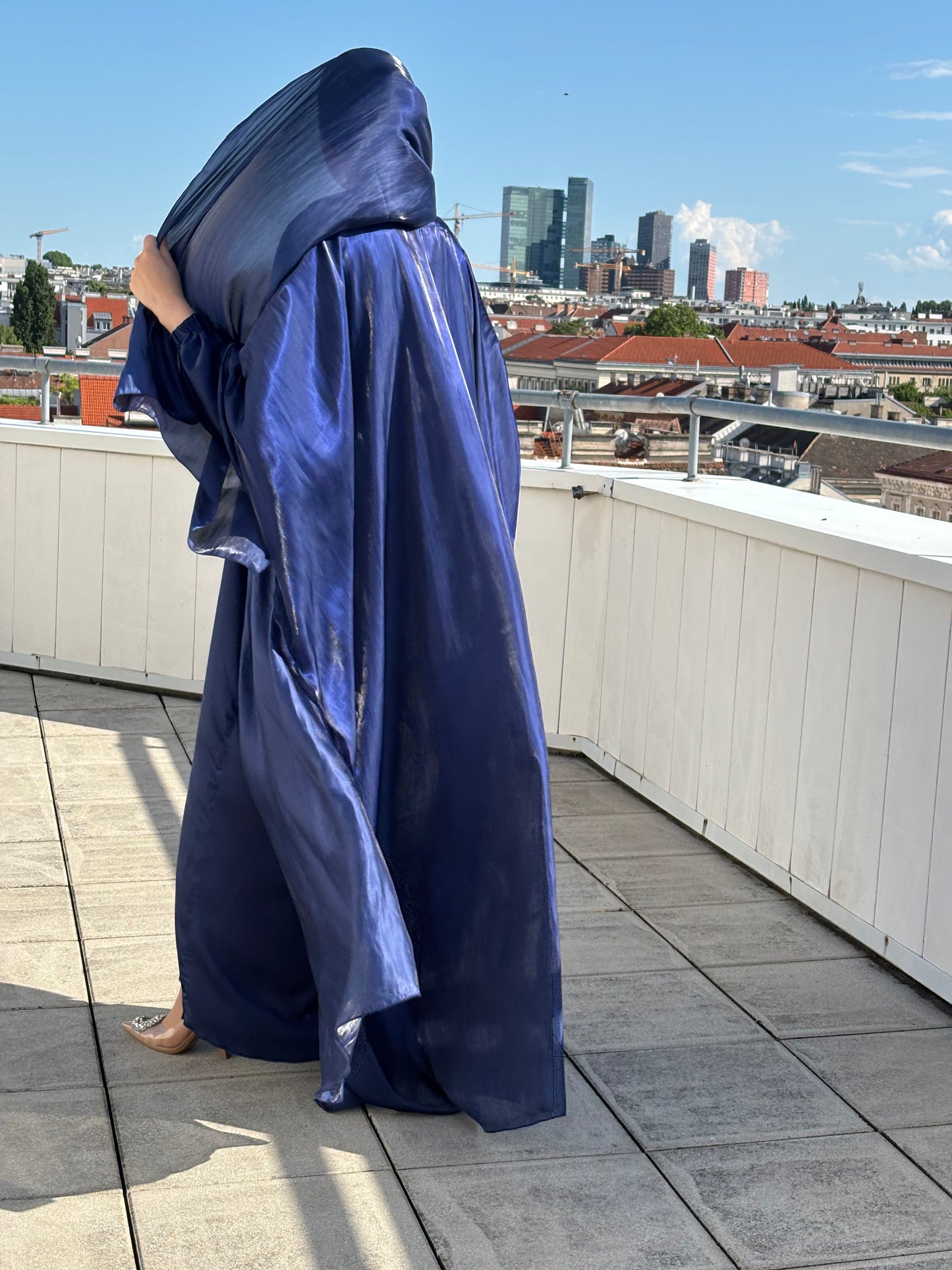 Abaya sherin in deep sapphire- rückenansicht im sonnenlicht mit organza stoff und stadtblick