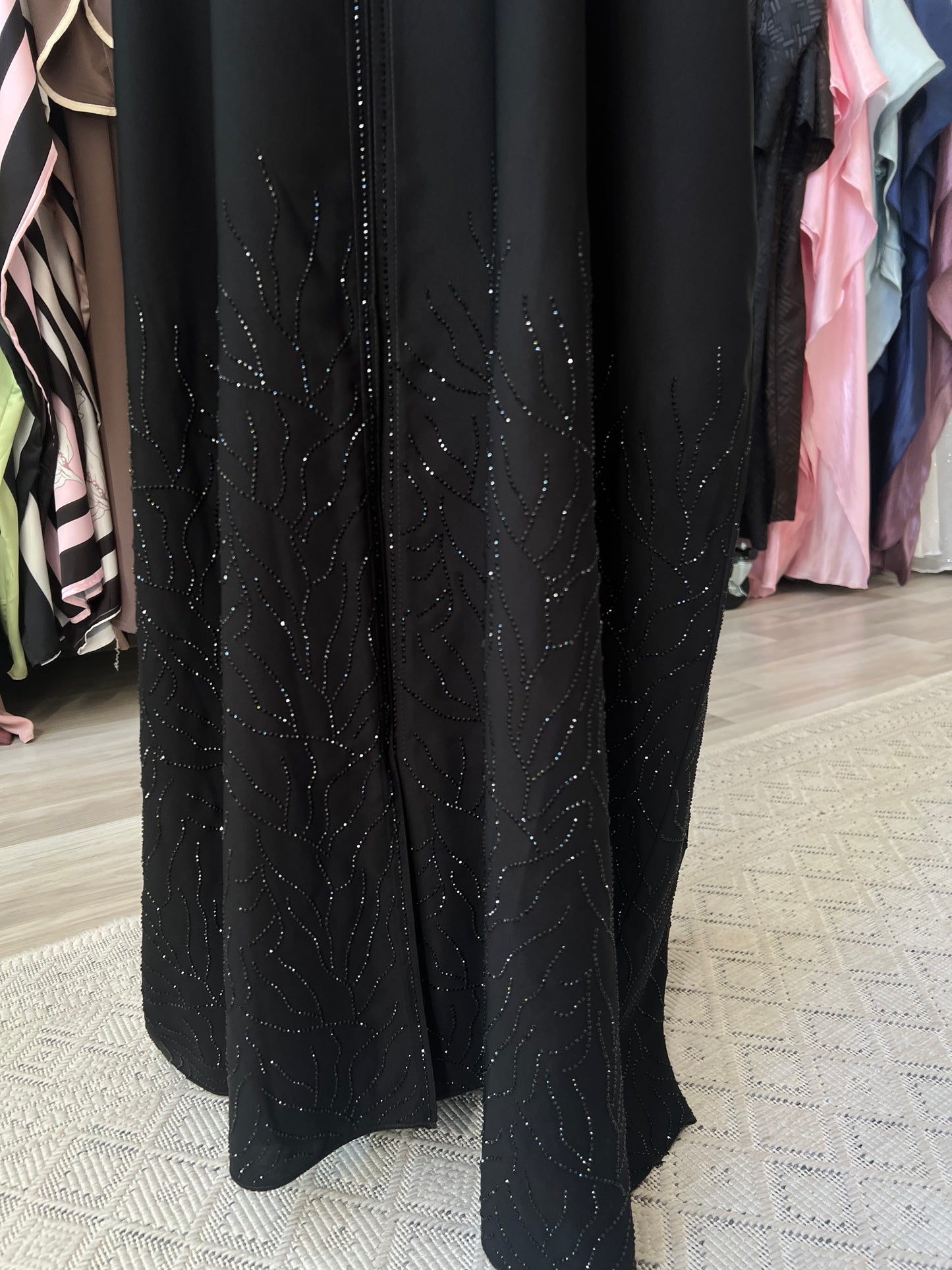 Detailansicht des unteren Saums der schwarzen Abaya Noura mit eleganter, feiner Glitzerverzierung.
