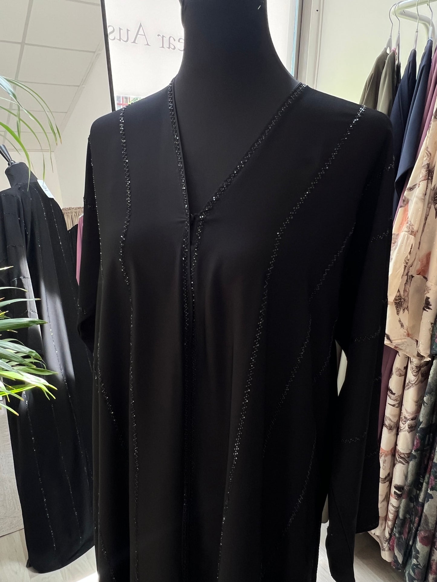 Detailaufnahme des oberen Teils der Abaya Salma mit funkelnder Glitzerlinie entlang des V-Ausschnitts und der Brustpartie.
