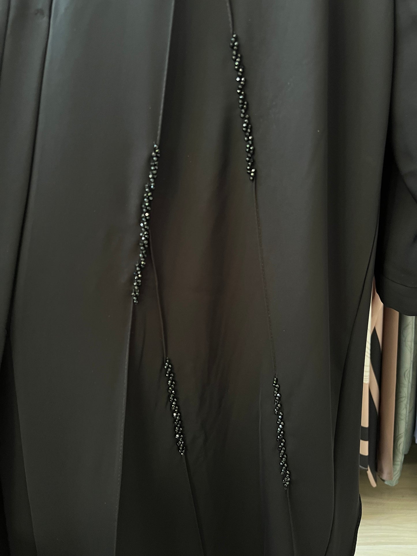 Detailaufnahme der schwarzen Perlenstickerei in vertikaler Anordnung auf dem Stoff der Abaya Zahra.