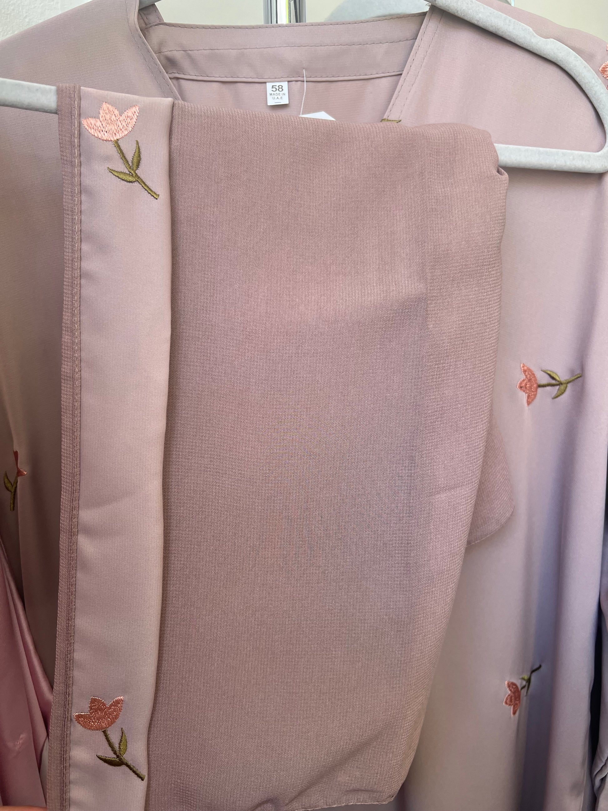 Passender Hijab zur Abaya, mit zarter floraler Stickerei am Rand – sorgfältig drapiert auf einem weißen Kleiderbügel.