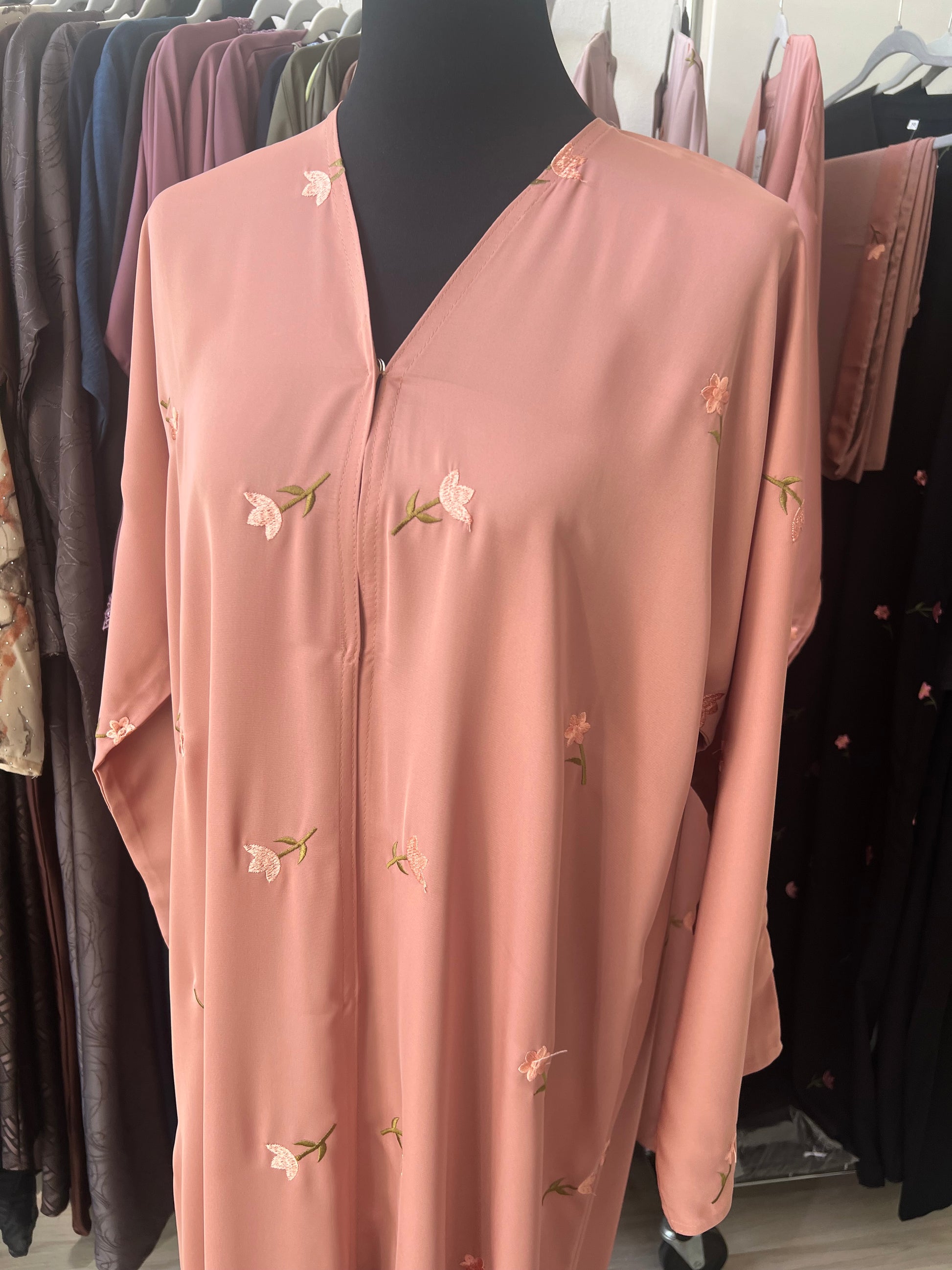 Detailaufnahme der Vorderseite der Abaya mit V-Ausschnitt und aufwendig bestickten kleinen Blüten in Rosa und Grün.