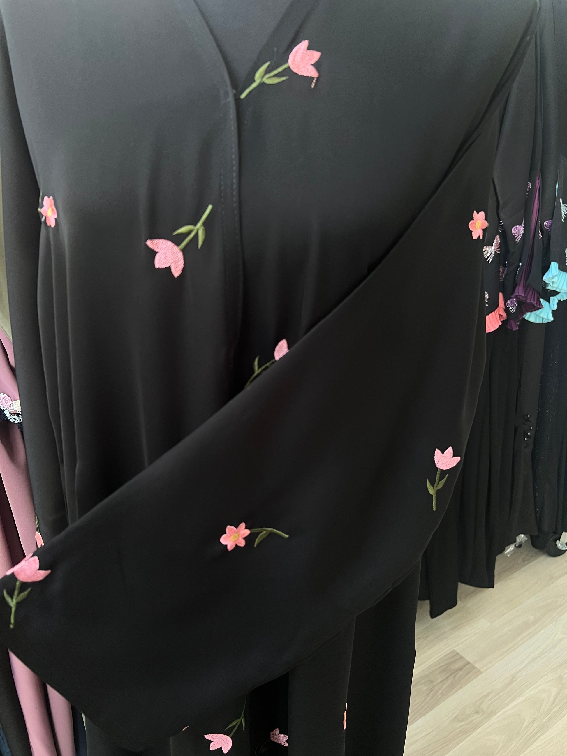 Detailaufnahme der Brust- und Ärmelpartie der schwarzen Abaya mit aufwendiger Blumenstickerei und passendem besticktem Ärmel.