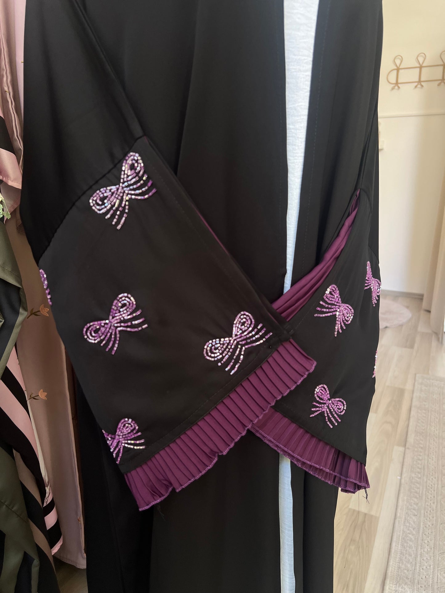 Vorderansicht des Kimonoärmels in verschränkter Pose – klare Sicht auf die detailreiche Stickerei und den plissierten Stoffeinsatz.