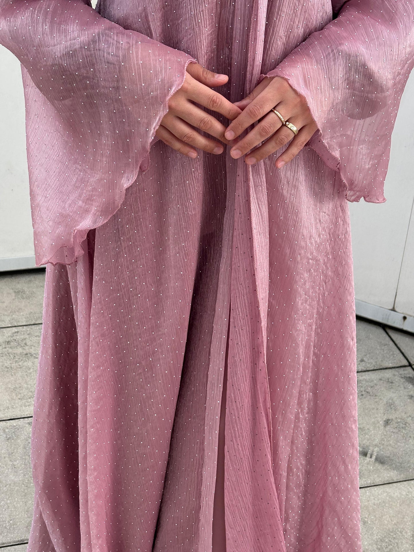 Detailaufnahme der Ärmel und Hände – schimmernde rosa Abaya mit Struktur