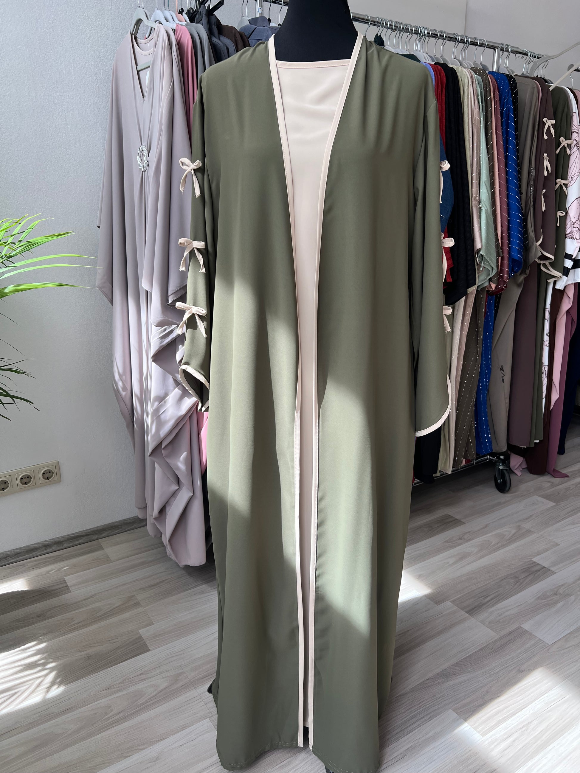 Khaki grüner mantel mit schleifen an den ärmel, kleid ist bodenlang und hat ein unterkleid in beige