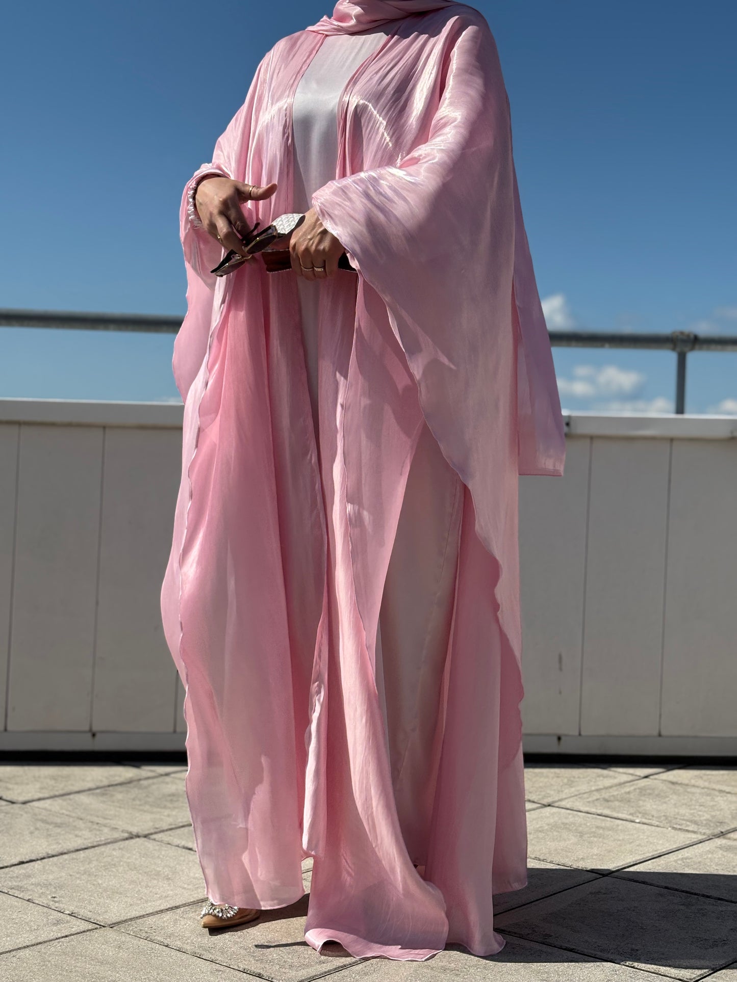 Detailansicht: glänzende Abaya in Rosé mit Clutch und Sonnenbrille