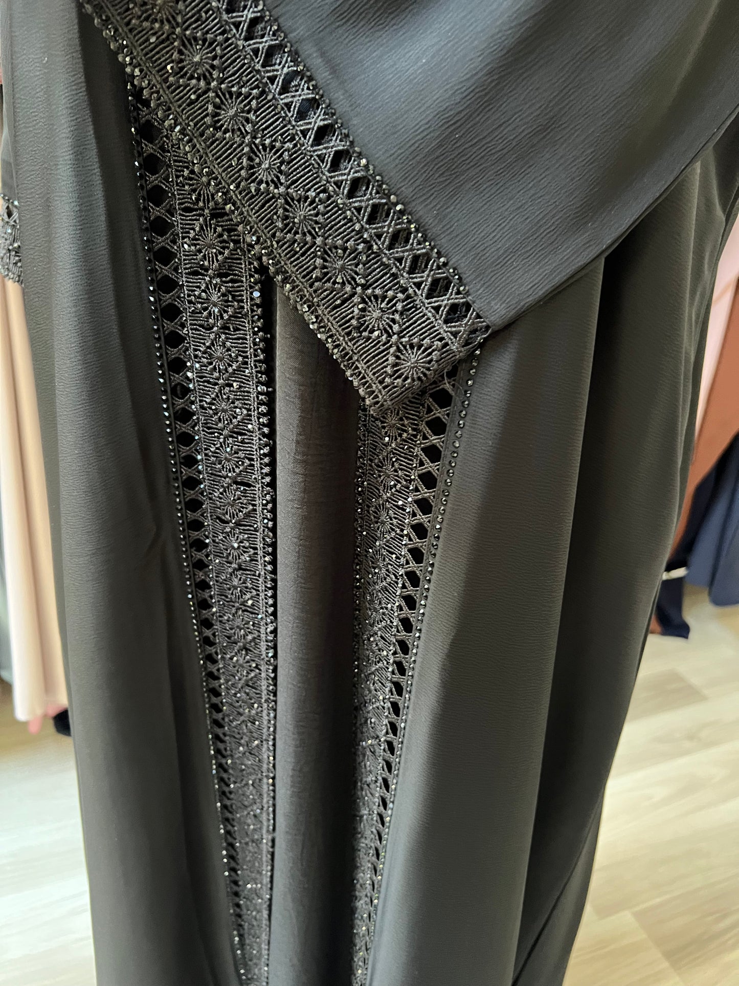 Nahaufnahme des verzierten Vorderteils der Abaya mit edler Glanzverarbeitung.