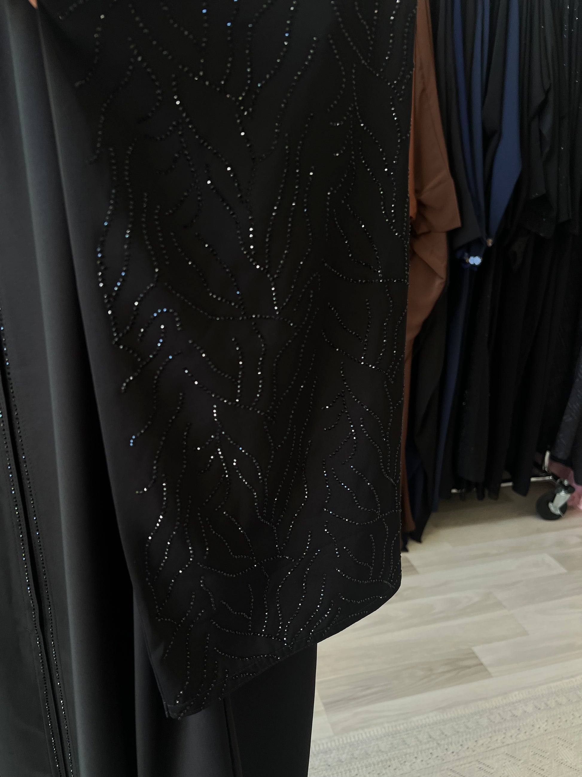 Nahaufnahme des Ärmels der Abaya Noura mit funkelnder Glitzersteinverzierung in organischem Muster.