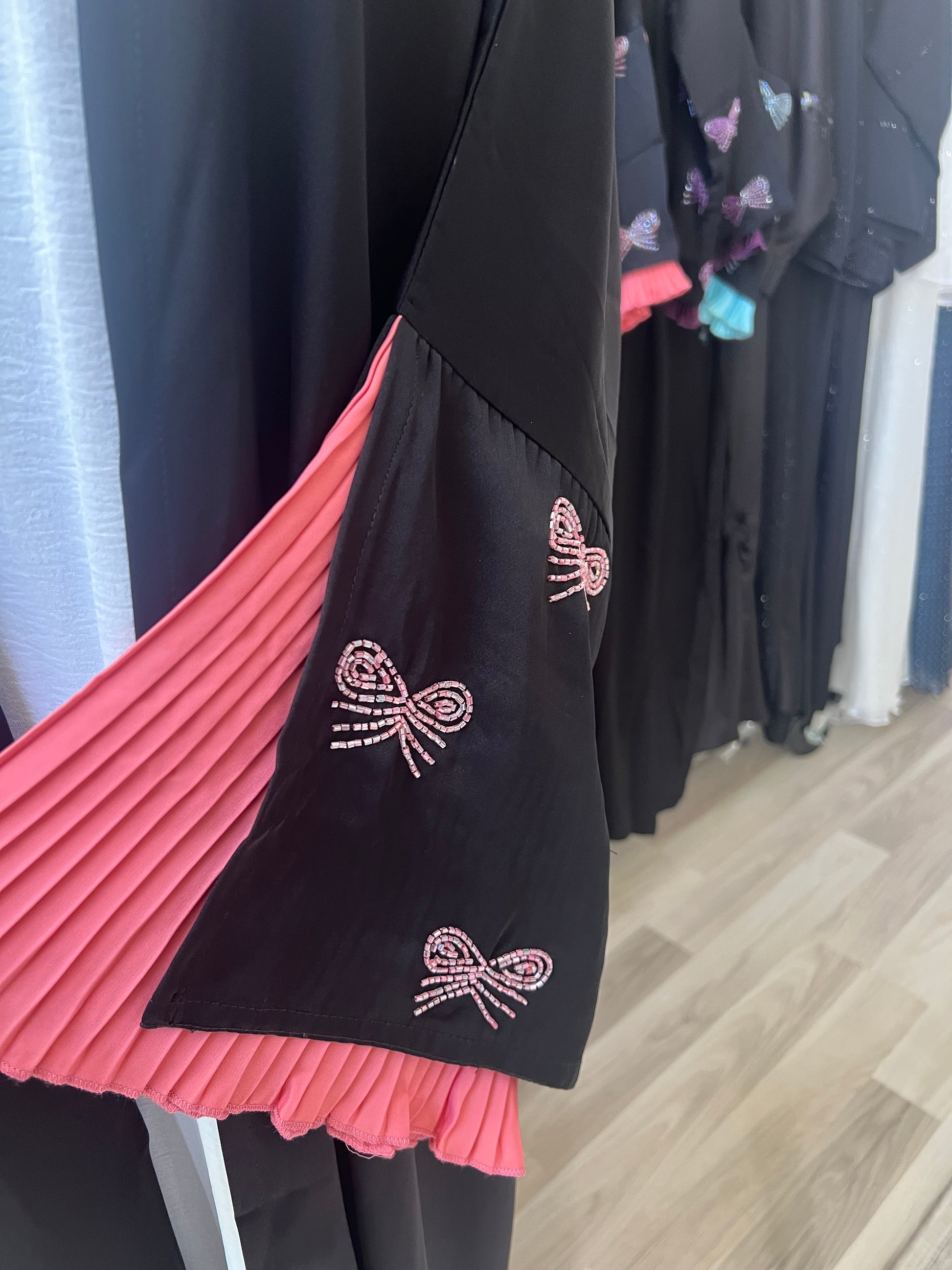 Detailansicht des Kimonoärmels mit funkelnden Schleifen aus Steinchen und pinkem Faltensaum – elegant und mädchenhaft zugleich.
