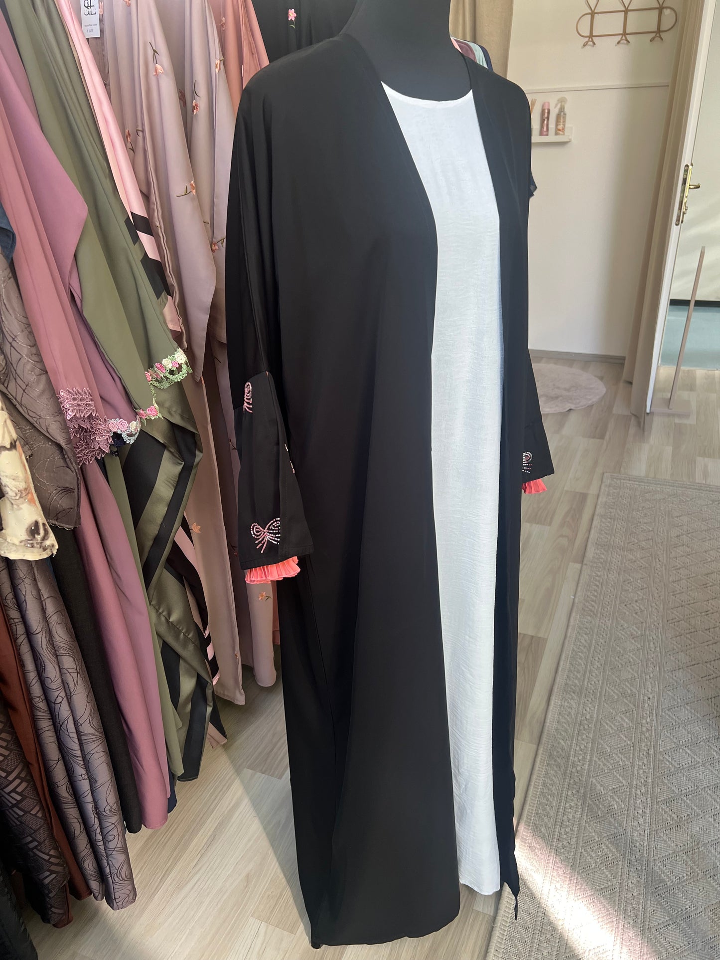 Seitliche Gesamtansicht des offenen schwarzen Kimonos mit langen Ärmeln und weißen Unterkleid – modernes, schlichtes Design mit femininen Details.
