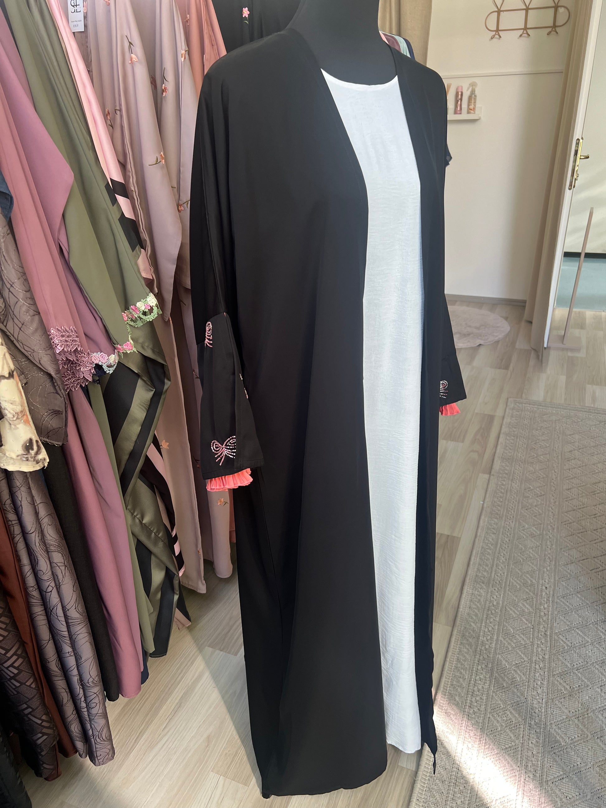 Seitliche Gesamtansicht des offenen schwarzen Kimonos mit langen Ärmeln und weißen Unterkleid – modernes, schlichtes Design mit femininen Details.