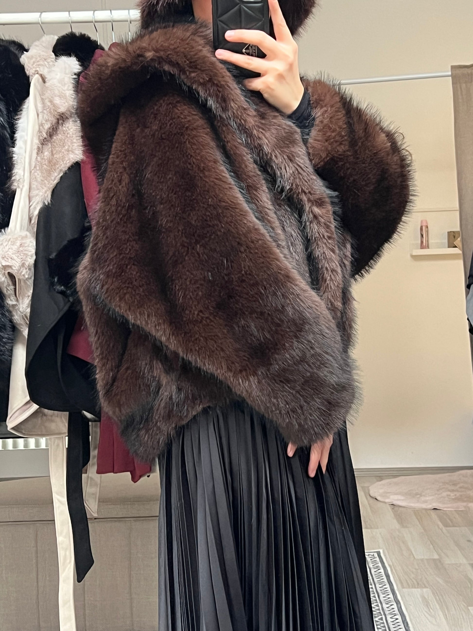 Detailaufnahme der dunkelbraunen Felljacke mit breiten Ärmeln aus flauschigem Kunstfell.