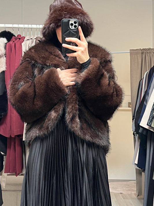 Dunkelbraune Felljacke für Damen mit voluminösem Kunstfell, getragen über schwarzem Outfit im Sheylin Showroom in Wien.