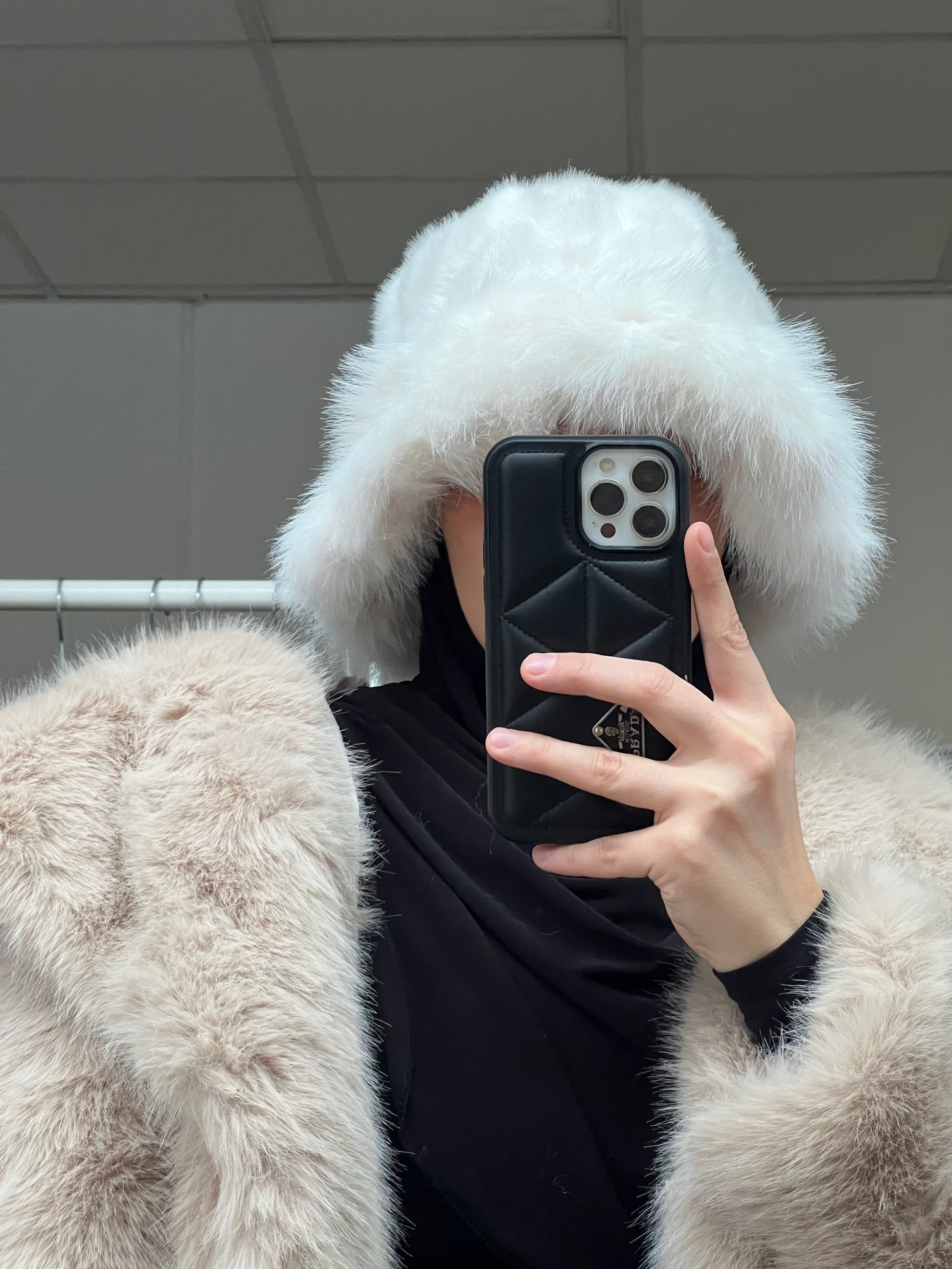 Weiße Fellmütze aus Kunstfell mit weicher Struktur, getragen mit schwarzem Hijab, Winteraccessoire für Damen